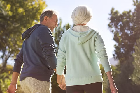 a retired couple holding hands outside